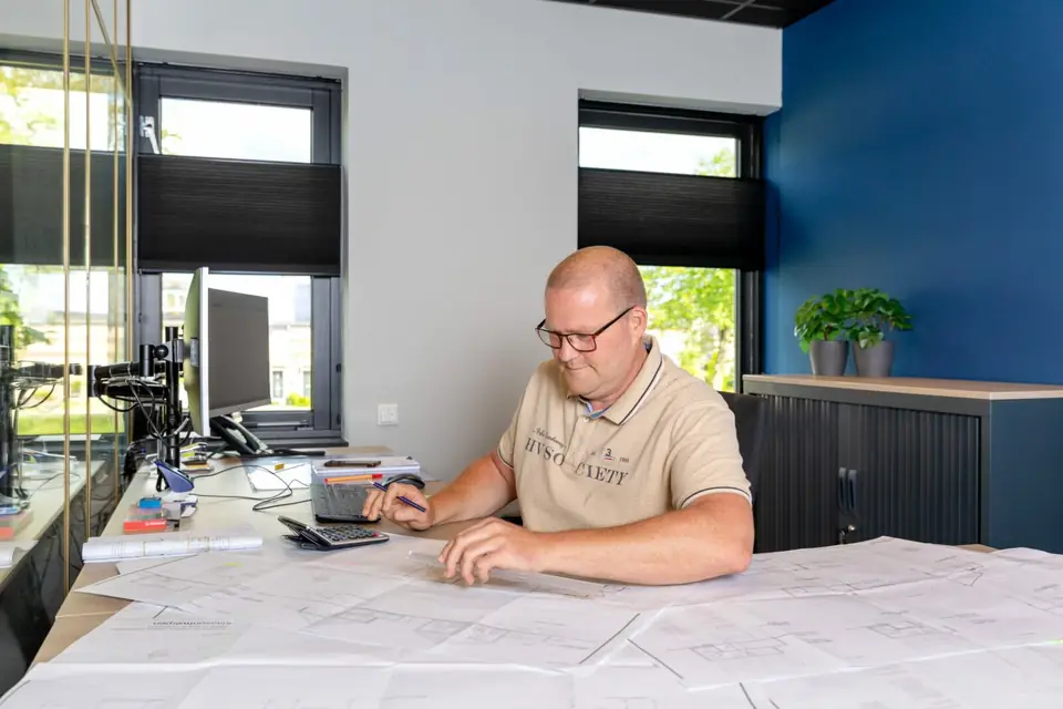 Medewerker van Osnabrugge buigt zich op kantoor over een bouwtekening